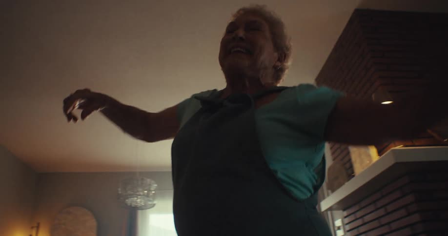 Happy elderly woman dancing in her living room having fun