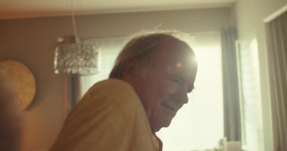 A joyful older couple dances romantically together indoors smiling and enjoying the moment