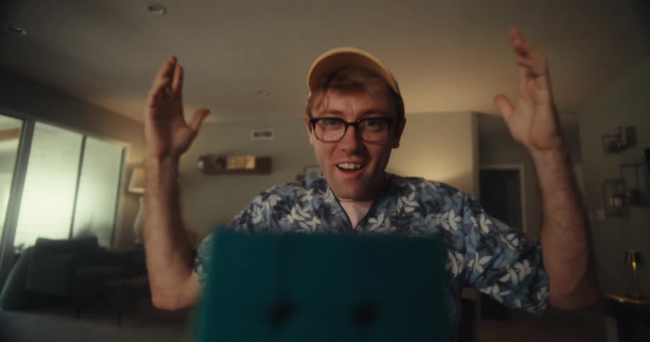 A man is surprised and celebrates after successfully solving a rubiks cube on a table