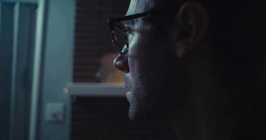 A man wearing glasses looks back and forth