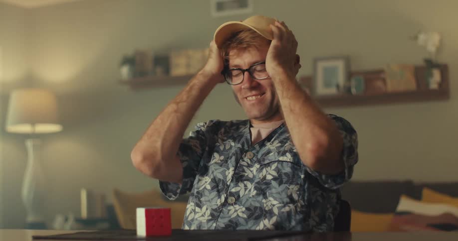 A man indoors excitedly celebrates solving a rubiks cube