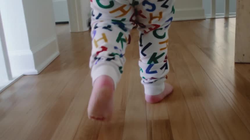 Legs of a toddler walking indoor at dawn