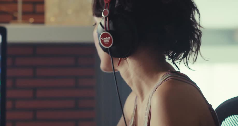 A woman is using a computer and listening to music