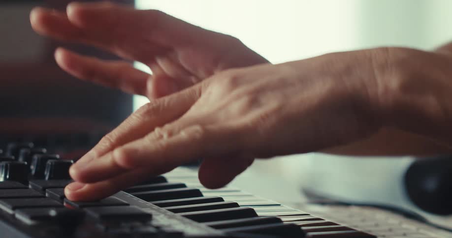 A mans hands are playing a keyboard and pushing random pads