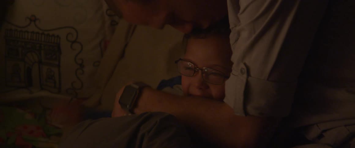 A man hugs and kisses his son in bed