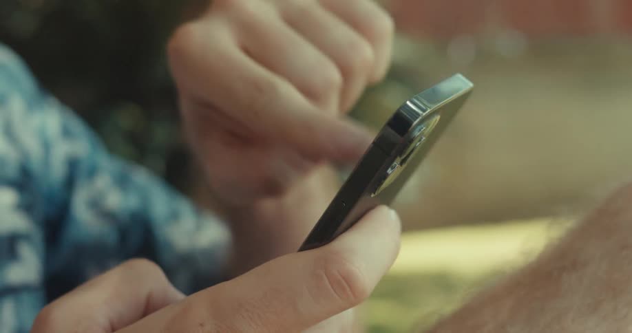Closeup of a mans hands using a smartphone outdoors