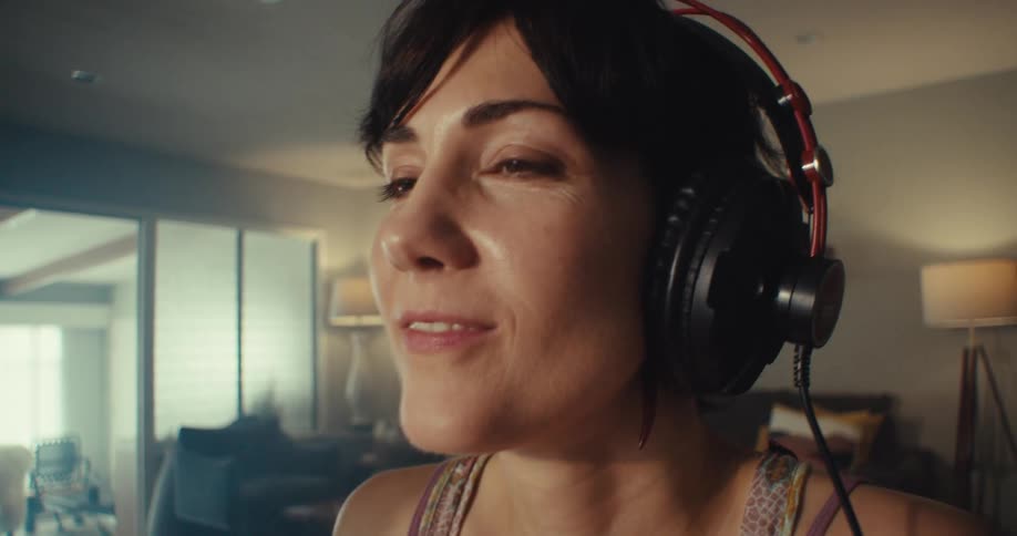 A woman is wearing headphones and using a soundboard
