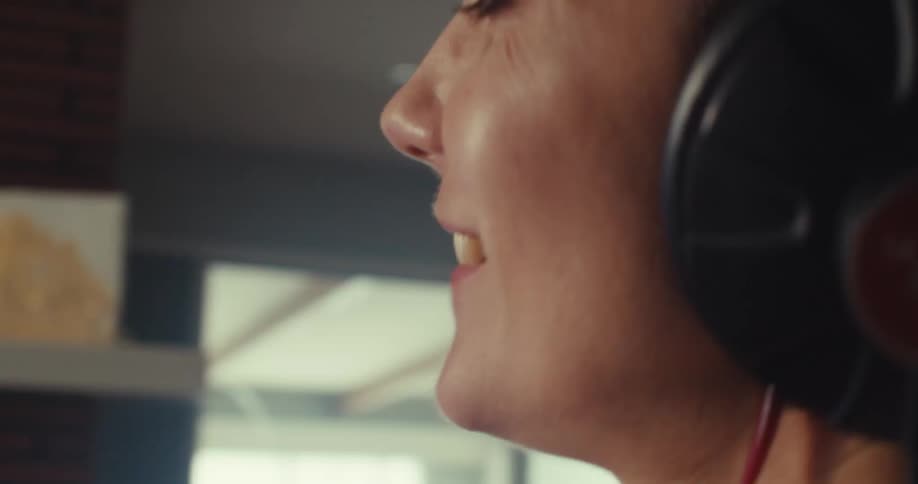 A woman sings while producing music on a computer