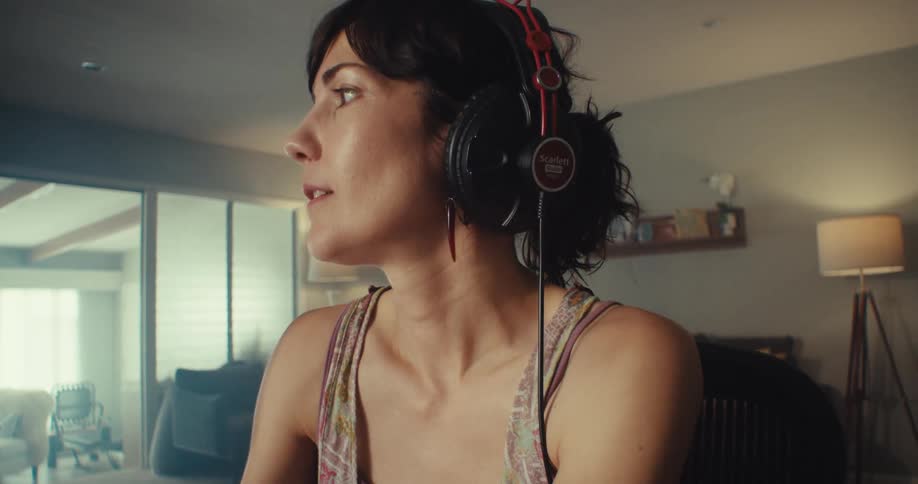 A woman wearing headphones grooves in her chair while lip synching to music