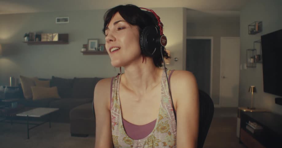 Lady seated on a chair indoor with headset on dances to music