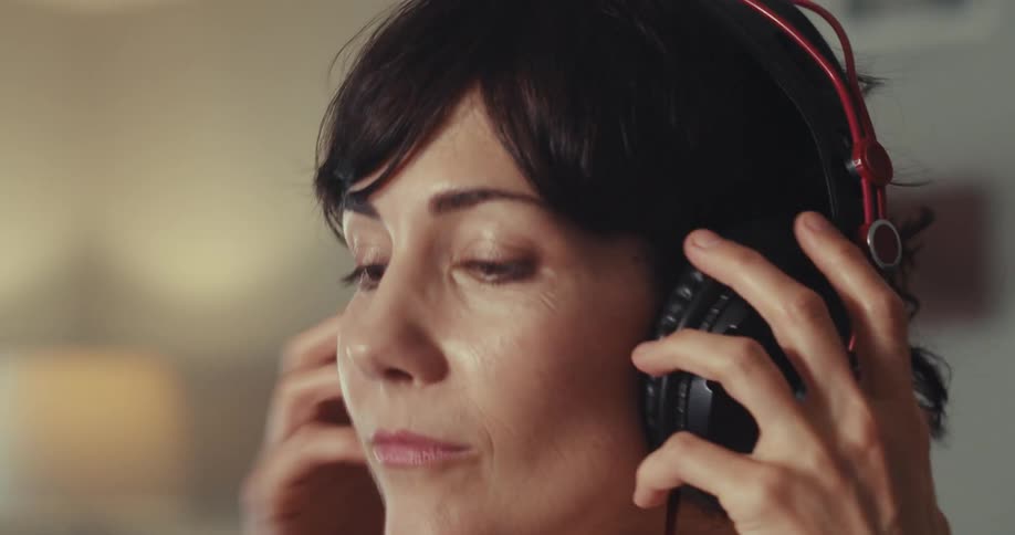 A woman listening to music removes her headphones