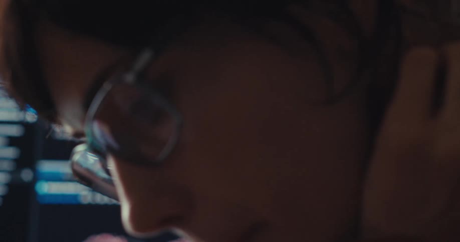A person wearing glasses is partially visible next to a computer screen displaying stock market data and graphs