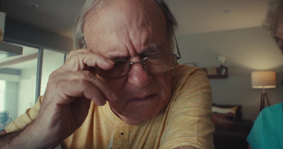 An older couple sits indoors deeply engaged in discussion while writing notes on paper