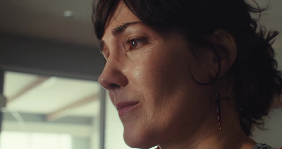 Woman frowns looking upset as she puts her hands to her face while at home