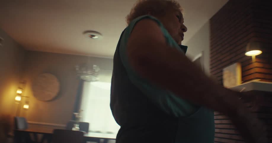 An older woman dances alone indoors happily and gracefully