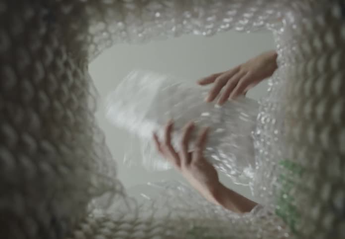 A man wraps an item in bubble wrap and places it in a box