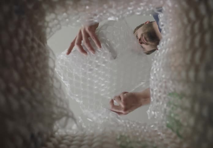 Poin of view man wrapping fragile item with bubble wrap into bubble wrap lined cardboard box