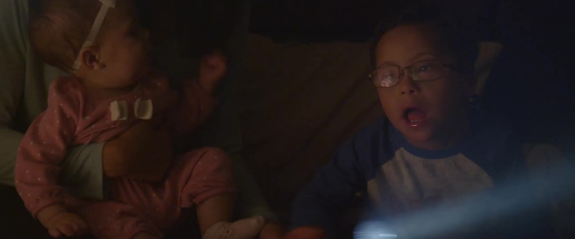 A young boy shines a flashlight with a baby girl nearby