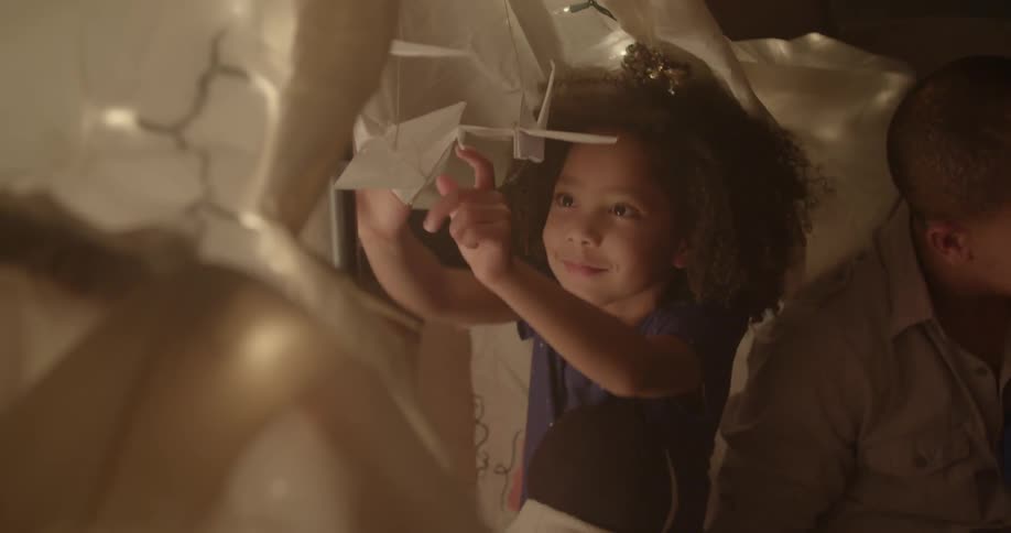 Girl plays with origami birds beside a man and child