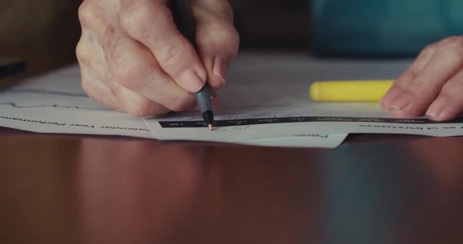 Elderly couple fills out paperwork while referencing a computer