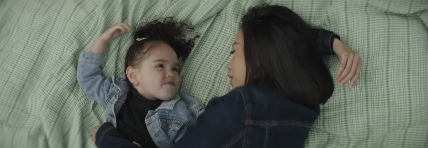 A mother and daughter are talking while laying down