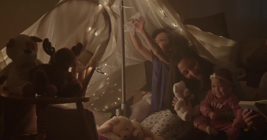 A child hangs paper birds under a tent with her family