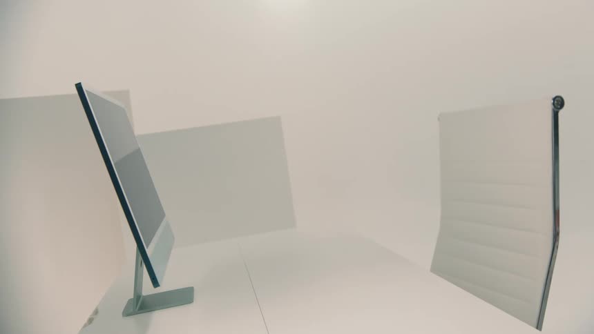 A minimalist workspace features a computer monitor and a white office chair against a neutral background