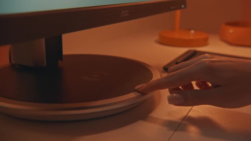 A person holding a pen sits in front of a computer monitor writing on a tablet