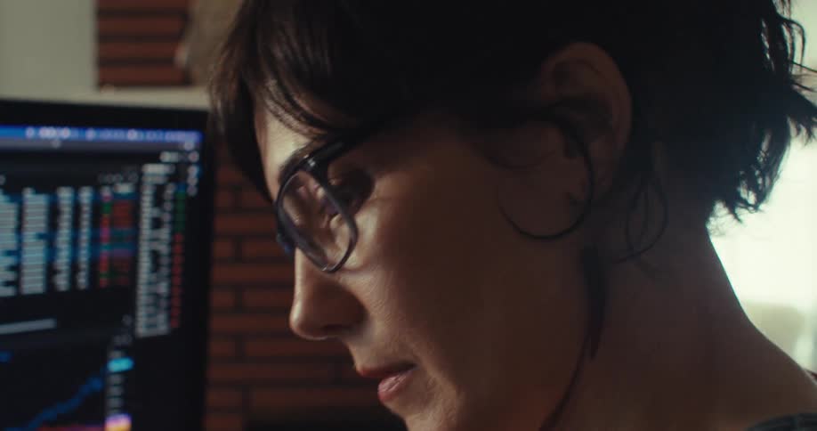Woman focuses on the information displayed on her computer while sitting at home during the daytime