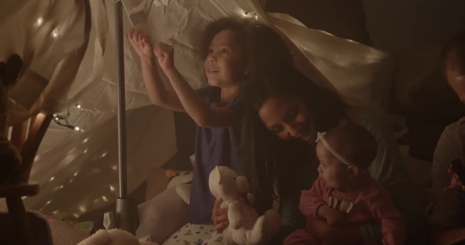 A family sits on the floor under a blanket tent