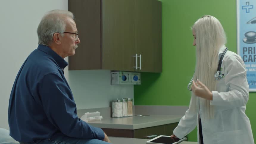 A blonde doctor placing a heart rate monitor around her neck while talking to an elderly patient sitting in front of her