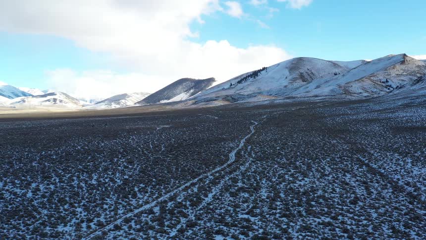 Snowy mountains span the horizon under a partly cloudy sky