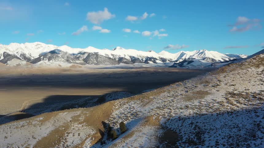 A mountain range has snow caps on the highest elevations