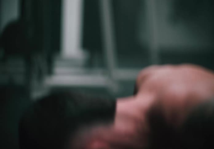 A man is doing pushups on a dark gym floor under moody lighting