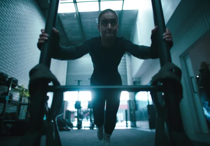 Woman exercises by pushing a heavy piece of exercise equipment