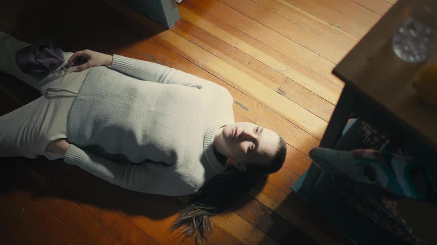 Woman lies on a wooden floor staring upwards