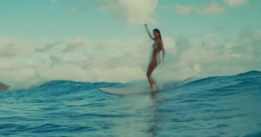 A woman surfing a wave in a bikini