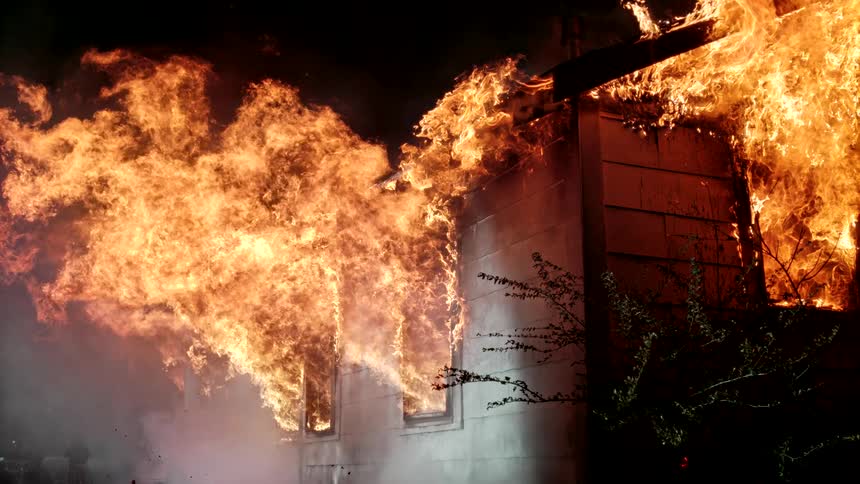 A house is engulfed in massive flames during a nighttime fire