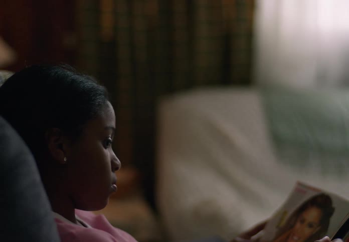 Girl reclining in the living room flips through a magazine during the daytime