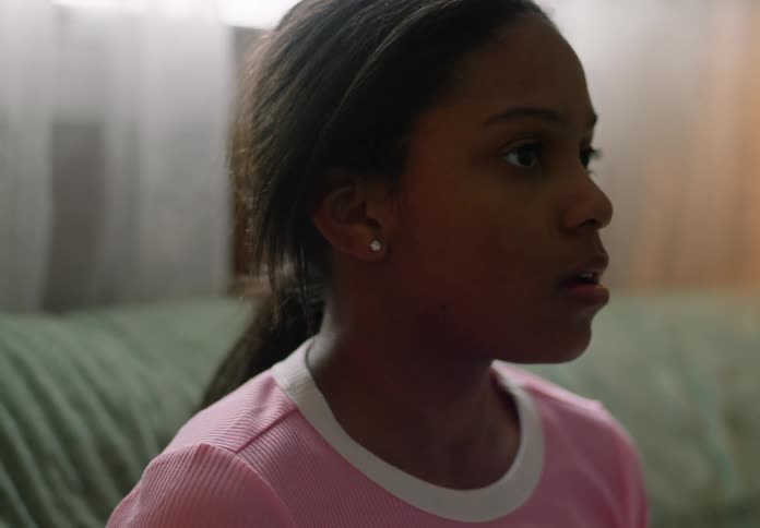 A young girl is sitting on a couch looking focused and thoughtful