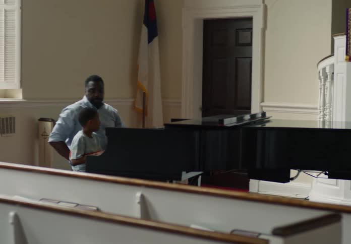 Son finishes the piano lesson supervised by his father on the church piano and runs out past his sister