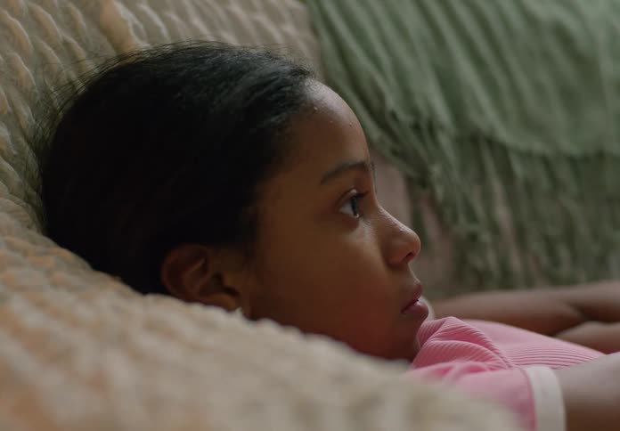 A girl lying on a sofa watching something