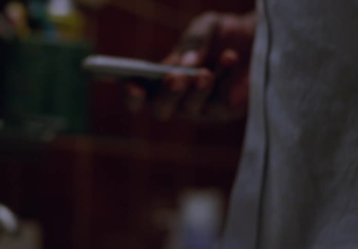 A woman picks up a cell phone placed on a desk and dials a number