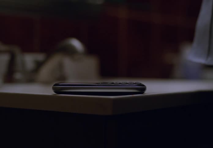 A woman picks up a cell phone placed on a desk and dials a number