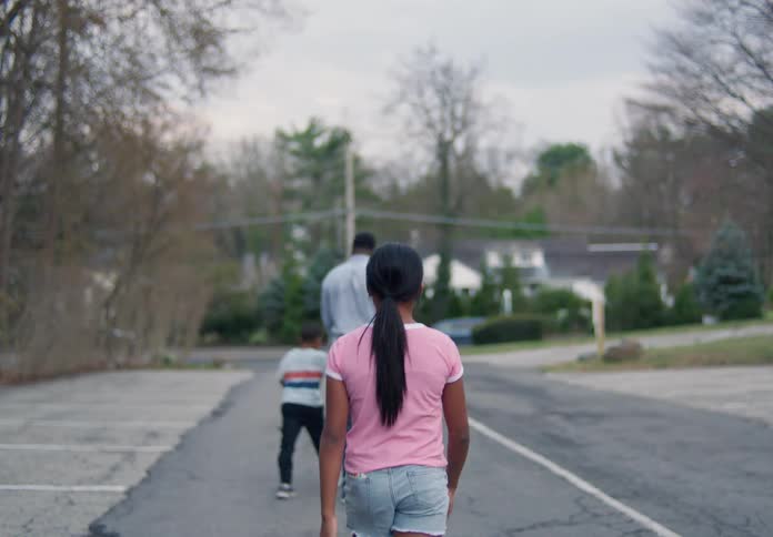 A girl gets out of the car and walks alone ahead a man walks hand in hand with a boy
