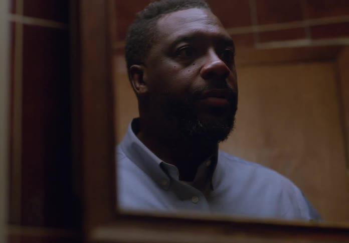 A man in a bathroom getting ready while looking at a mirror