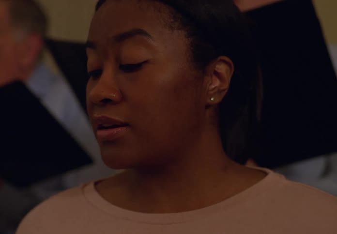 A woman singing in a group of people in a choir