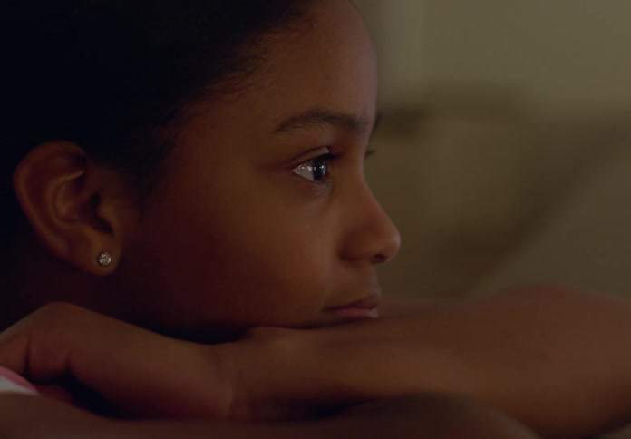 A little girl leans on her arms on a countertop looking deep in thought