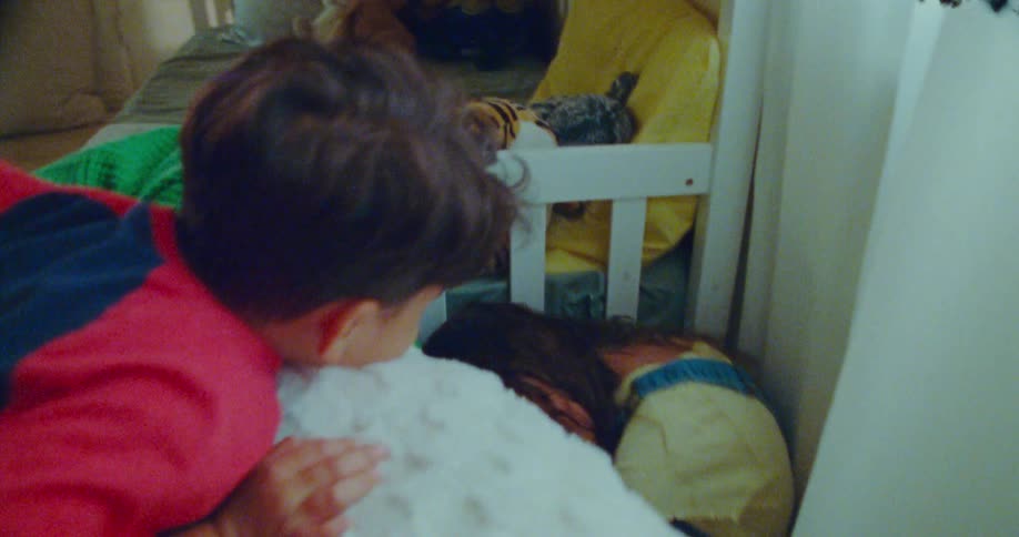 A child climbs over a couch and discovers a girl hiding in a sunny room during a game of hide and seek
