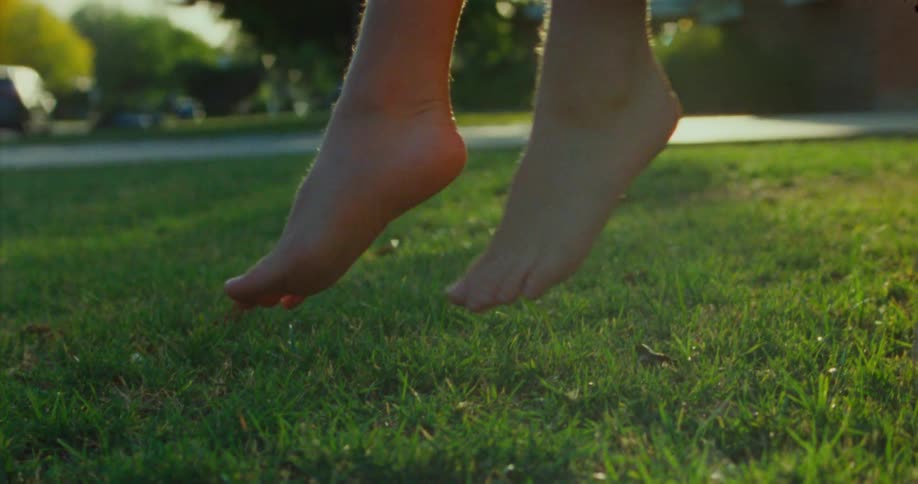 Close up of a persons feet hanging in the grass